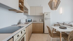 Ett modernt kök med en svart bänkskiva, träskåp, en inbyggd mikrovågsugn och ett vitt kylskåp.