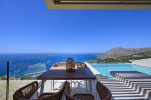 Eine Terrasse mit Tisch und Stühlen mit Blick auf ein Schwimmbad und das Meer.