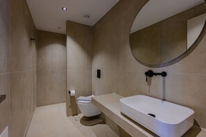 Ein modernes Badezimmer mit Toilette, Waschbecken und Spiegel.