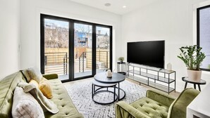 Una sala moderna con un sofá verde, una mesa de centro redonda y un televisor de pantalla plana.