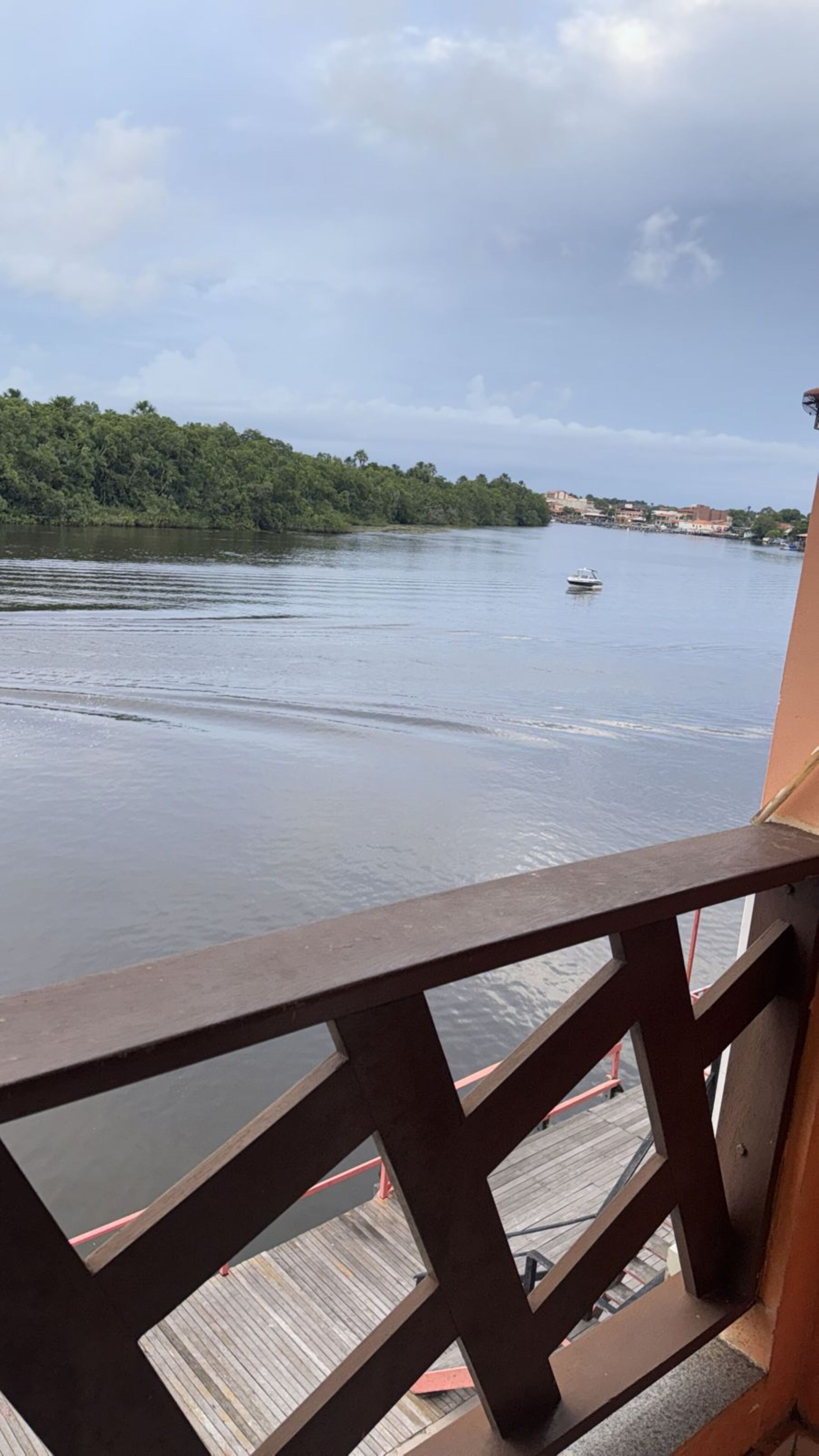 A river view from a balcony with a wooden railing.