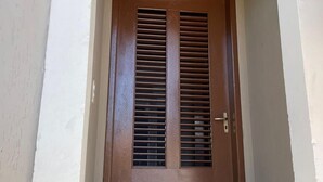 A brown door with a central panel and vertical slats, set in a white-framed archway. - Hotel Beira Rio Preguiças (Barreirinhas)