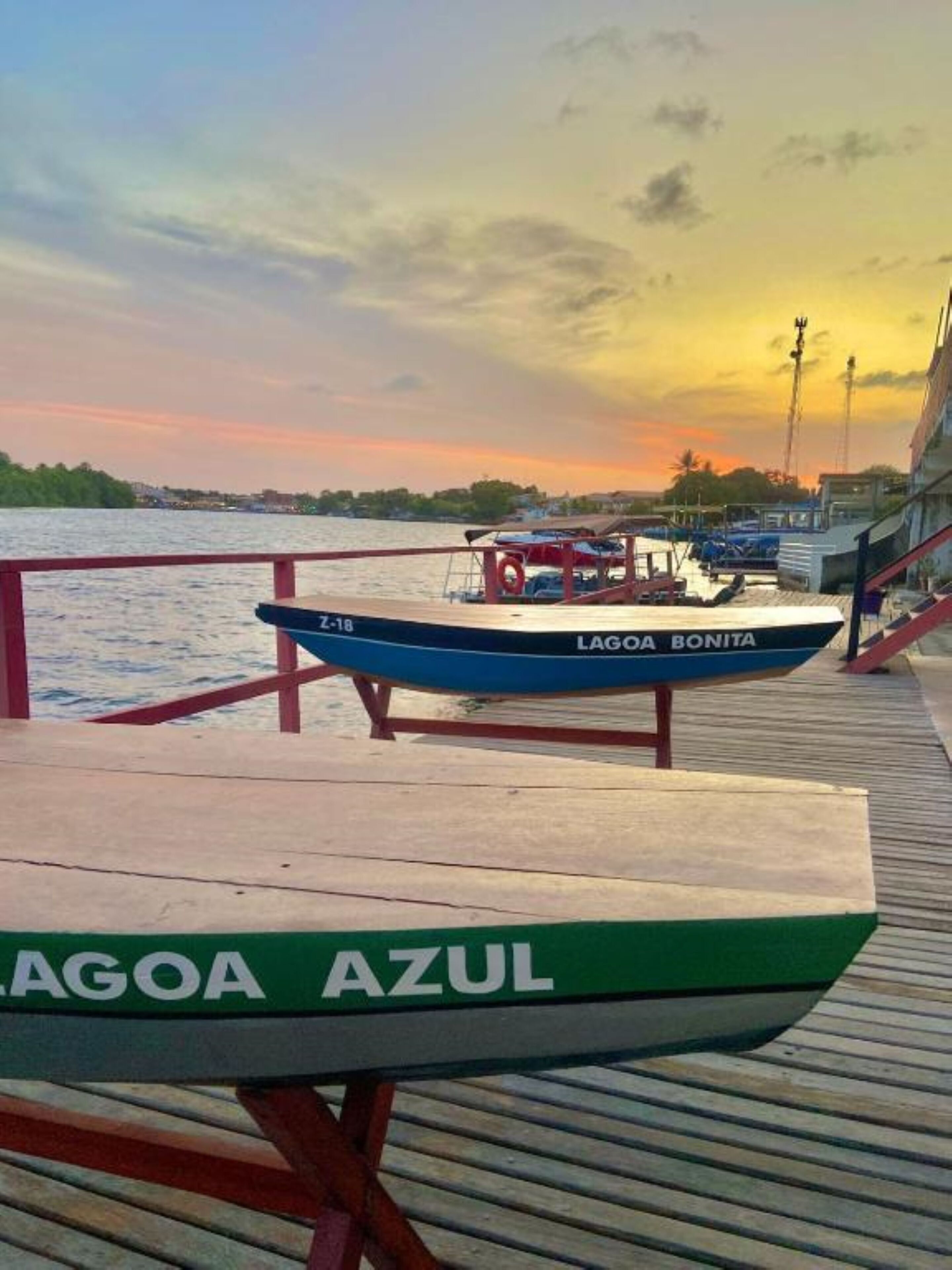 Un barco llamado "LAGOA BONITA" atracado en un muelle con vistas a la puesta de sol sobre el agua.