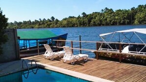 A swimming pool with lounge chairs and a view of a lake. - Hotel Beira Rio Preguiças (Barreirinhas)