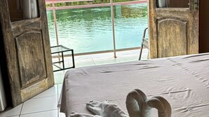 A hotel room with a bed, a view of a water body, and an air conditioning unit. - Hotel Beira Rio Preguiças (Barreirinhas)