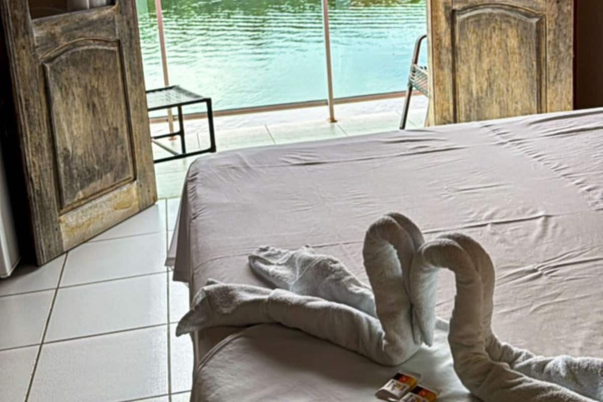 Une chambre d’hôtel avec un lit, une vue sur un plan d’eau et un appareil de climatisation.