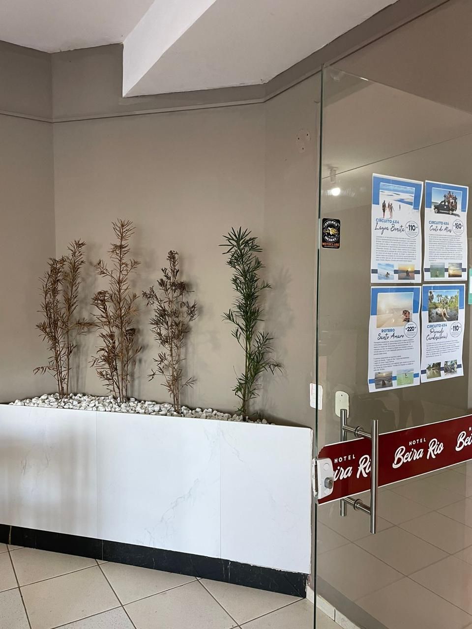 A reception area with a glass partition, a reception desk, and informational posters on the wall.