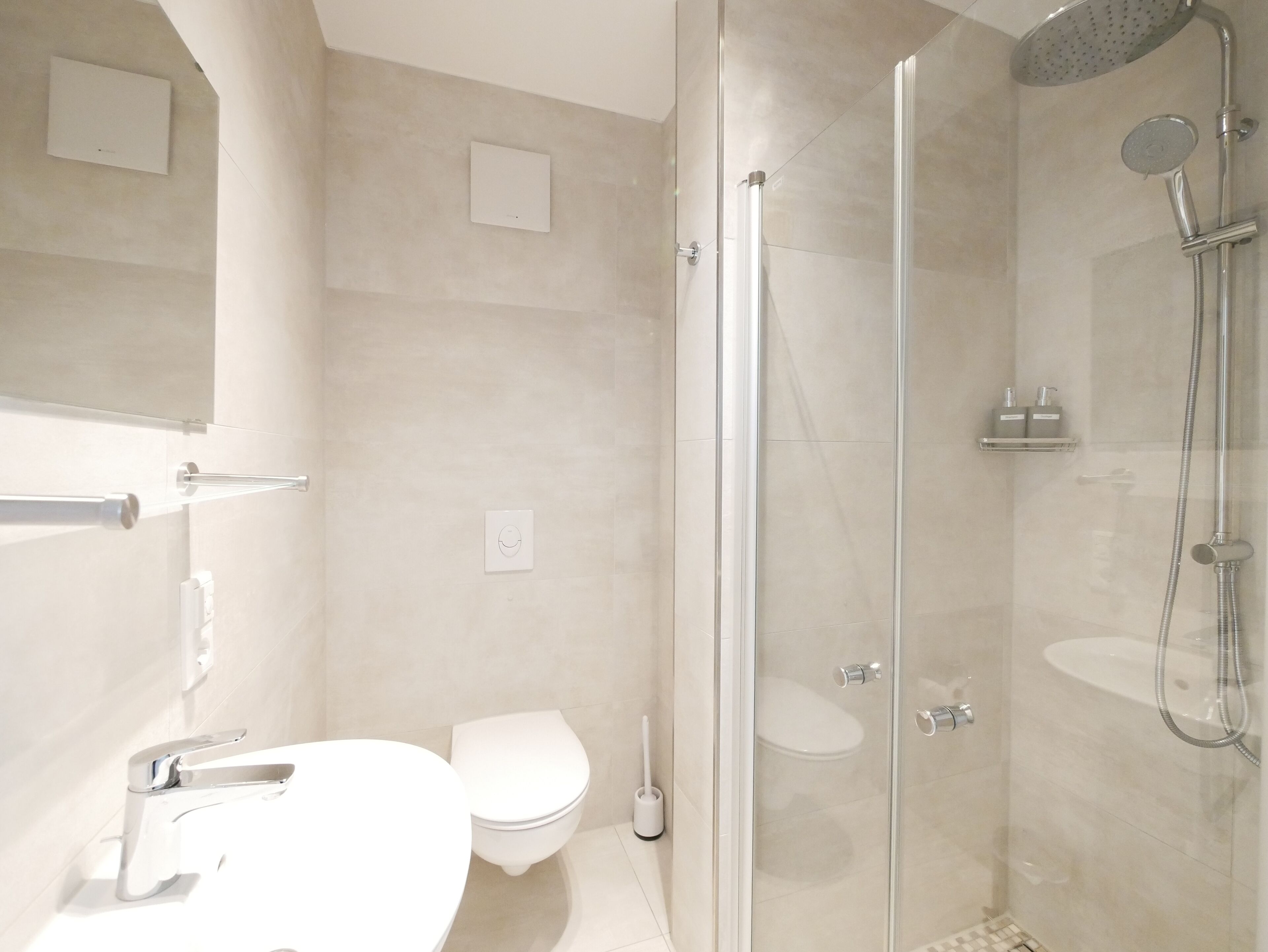 A modern bathroom with a glass-enclosed shower, a toilet, and a sink.