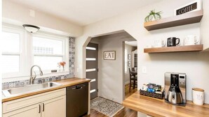 A modern kitchen with a dishwasher, a coffee maker, and a sign that says "EAT".