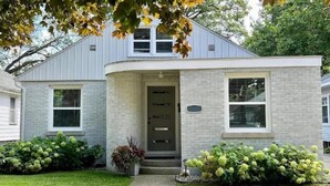 A two-story house with a brick facade, a front door, and a small porch.