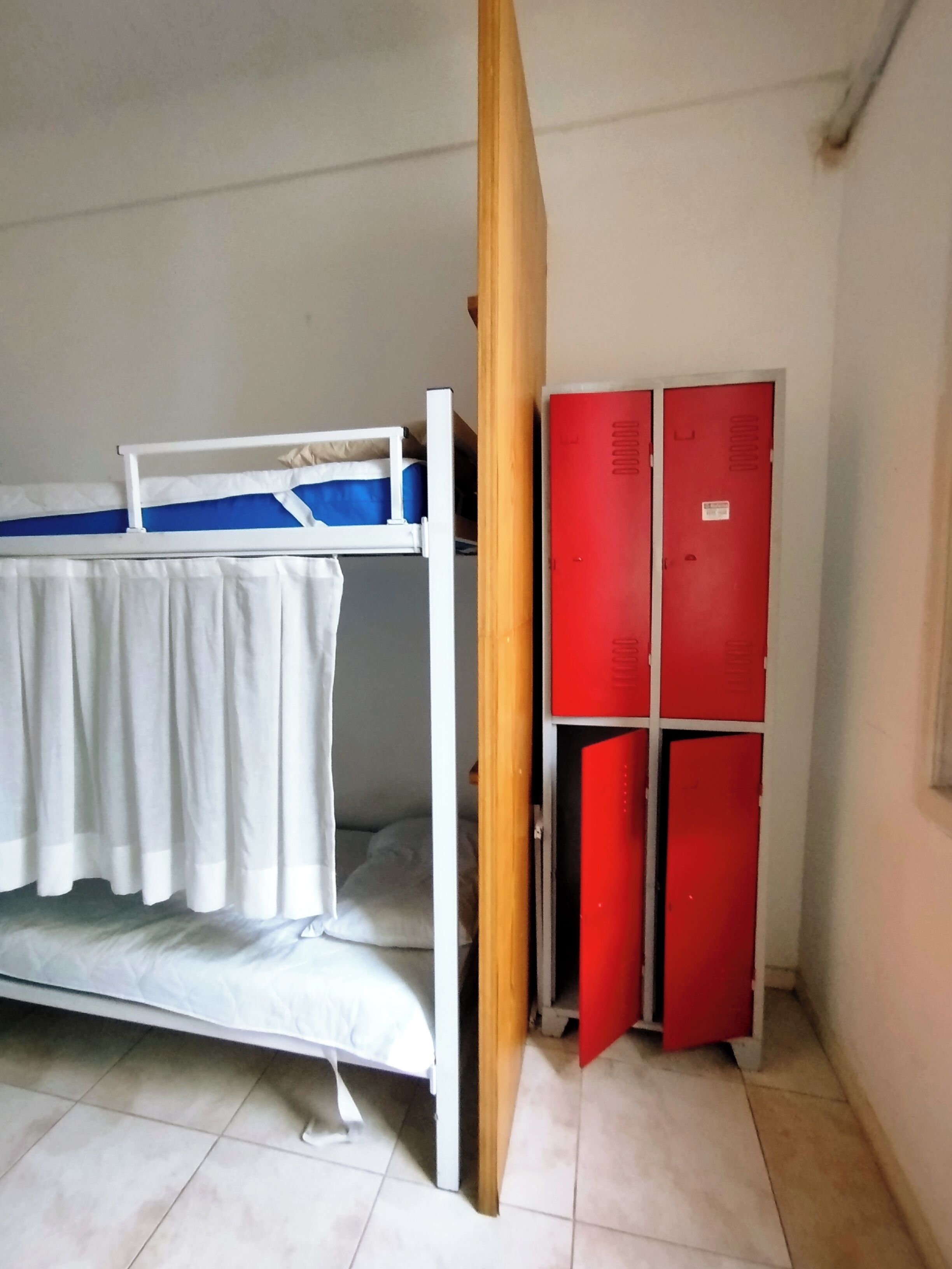 A room with a bunk bed, a wooden door, and red lockers.