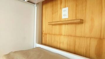 Una cama litera con cabecera de madera y una pared blanca a un lado.
