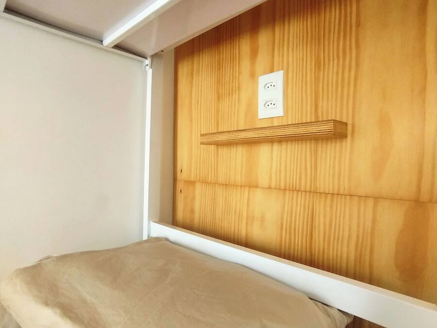 Una cama litera con cabecera de madera y una pared blanca a un lado.