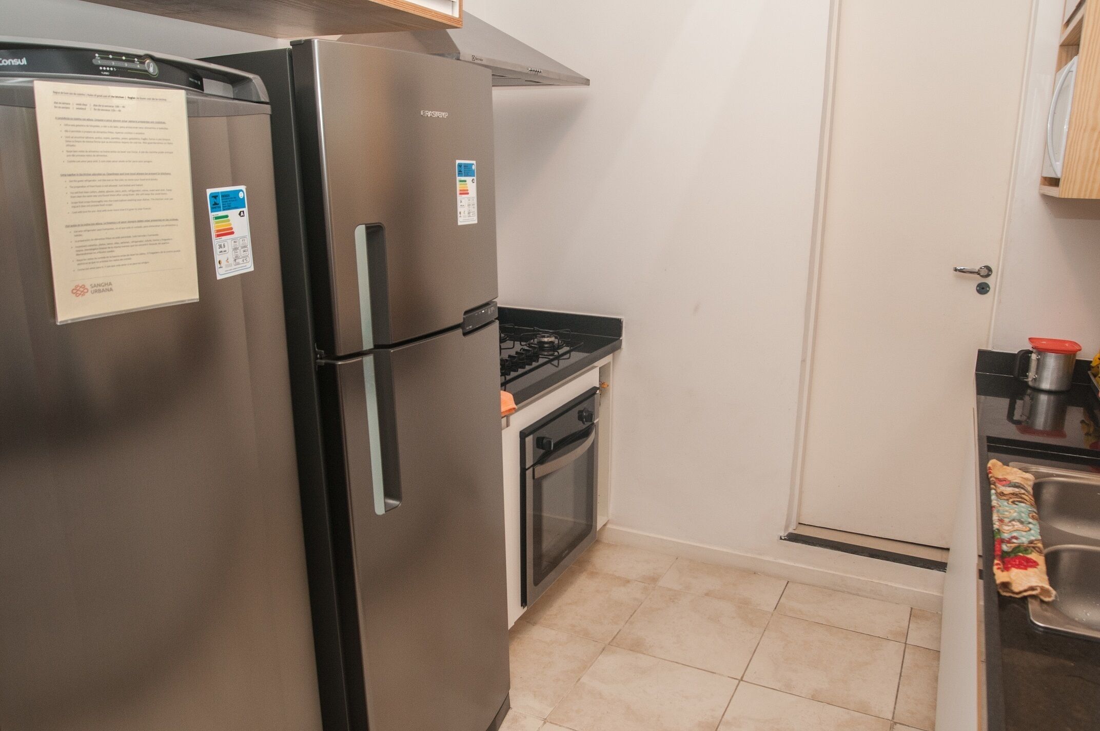 A compact kitchen with a stainless steel refrigerator, a built-in oven, and a gas stove.