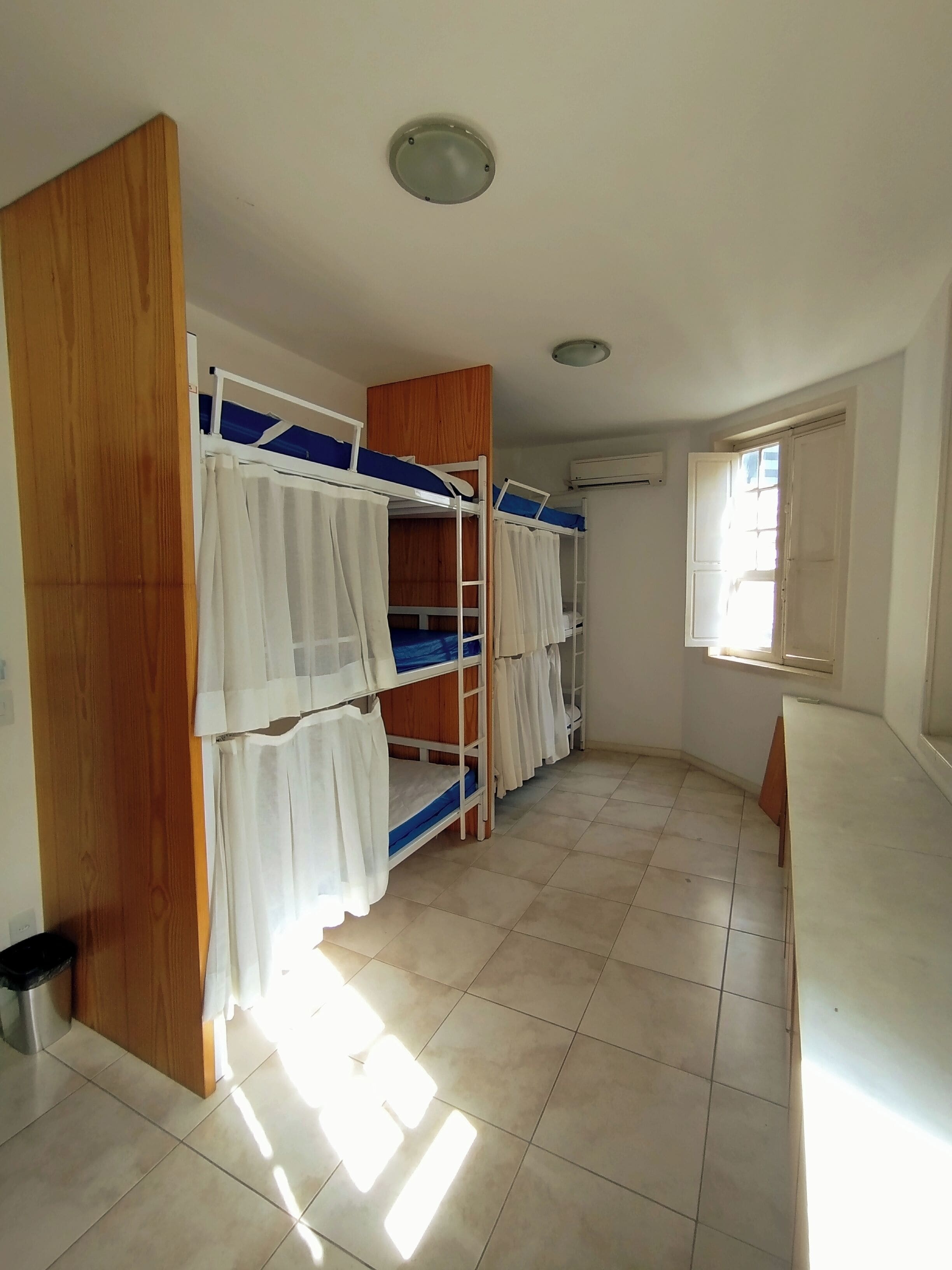 A room with bunk beds, a window, and a ceiling light.