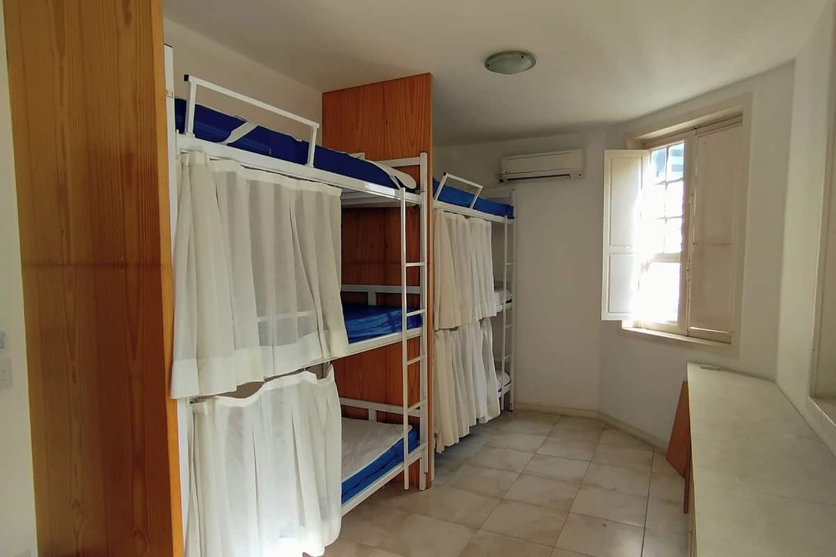 A room with bunk beds, a window, and a ceiling light.