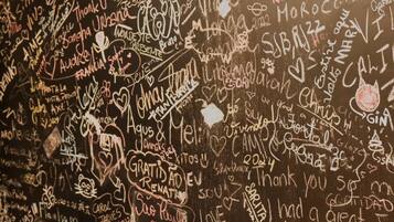 A wall covered with various handwritten messages and drawings, including names, dates, and doodles.