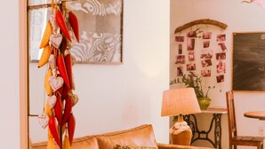 A brown leather sofa with floral cushions, a hanging plant with red and yellow leaves, and a mirror reflecting the room. - Sangha Urbana - hostel, yoga & meditation (Rio de Janeiro)