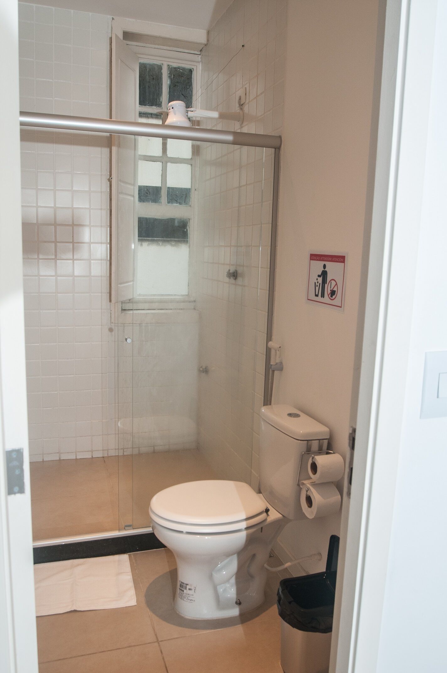 A bathroom with a toilet, shower, and a hand dryer.