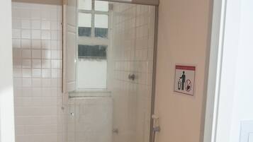 A bathroom with a toilet, shower, and a hand dryer.