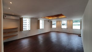 A spacious room with a high ceiling, wooden flooring, and multiple windows providing natural light. - Sangha Urbana - hostel, yoga & meditation (Rio de Janeiro)