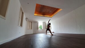 A spacious room with a high ceiling and wooden paneling, large windows, and a dark wooden floor. - Sangha Urbana - hostel, yoga & meditation (Rio de Janeiro)