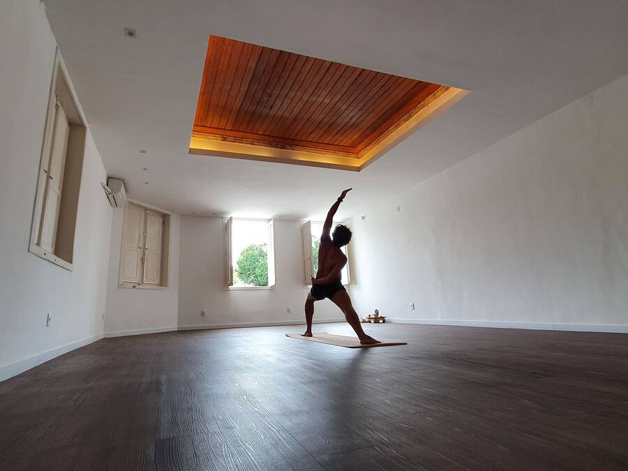 Una habitación amplia con techo alto y paneles de madera, ventanas grandes y piso de madera oscura.