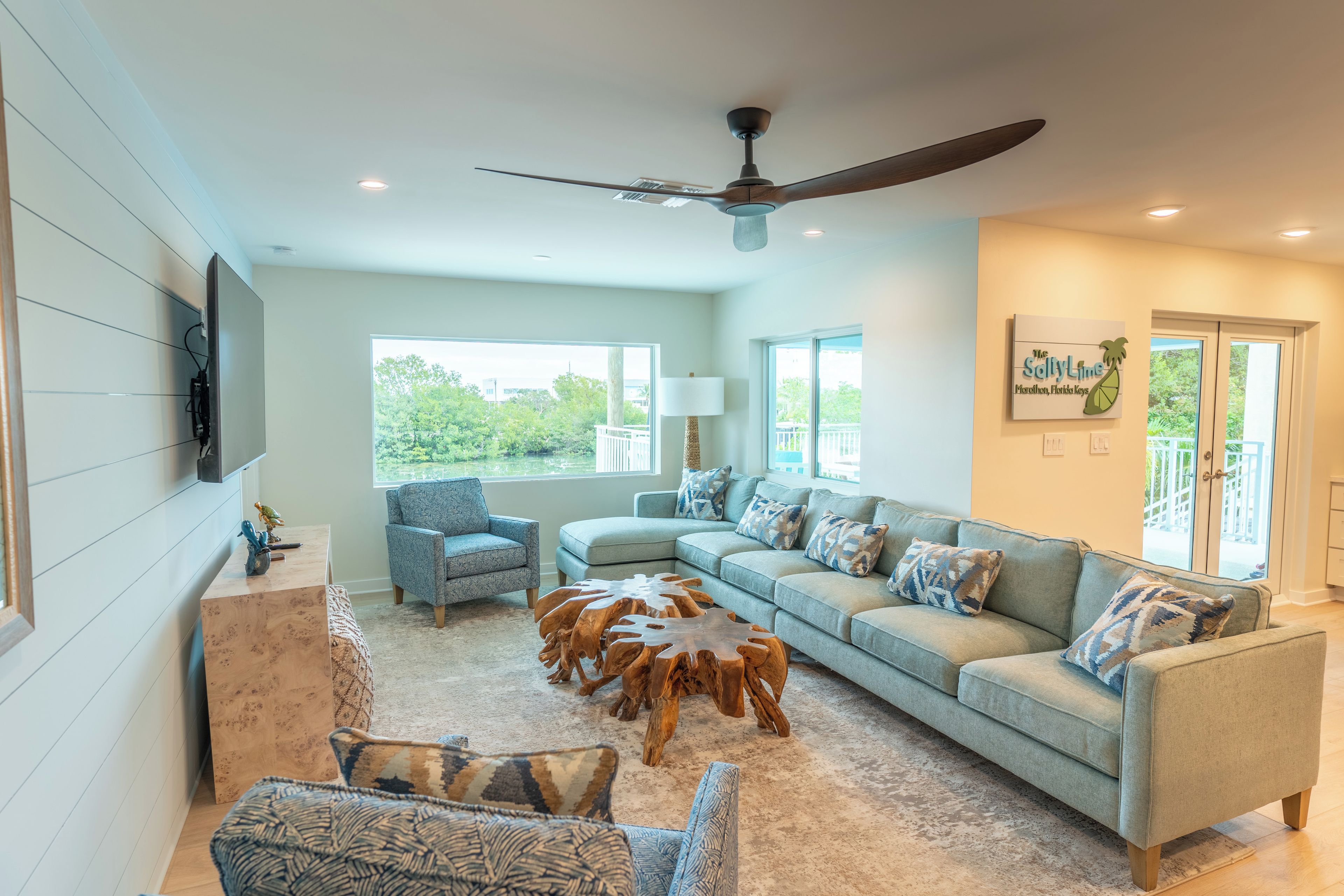 A spacious living room with a large sofa, a coffee table, and a ceiling fan.