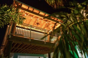 A two-story building with a balcony, wooden beams, and string lights.