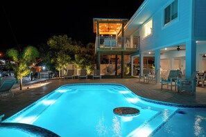 Une piscine avec un jacuzzi, entourée de chaises longues et d’une zone aménagée pour se détendre.