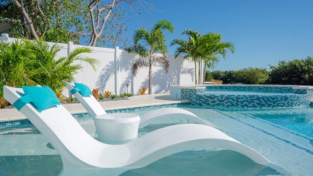 Ein Pool mit weißen Liegestühlen und einem weißen Zaun.