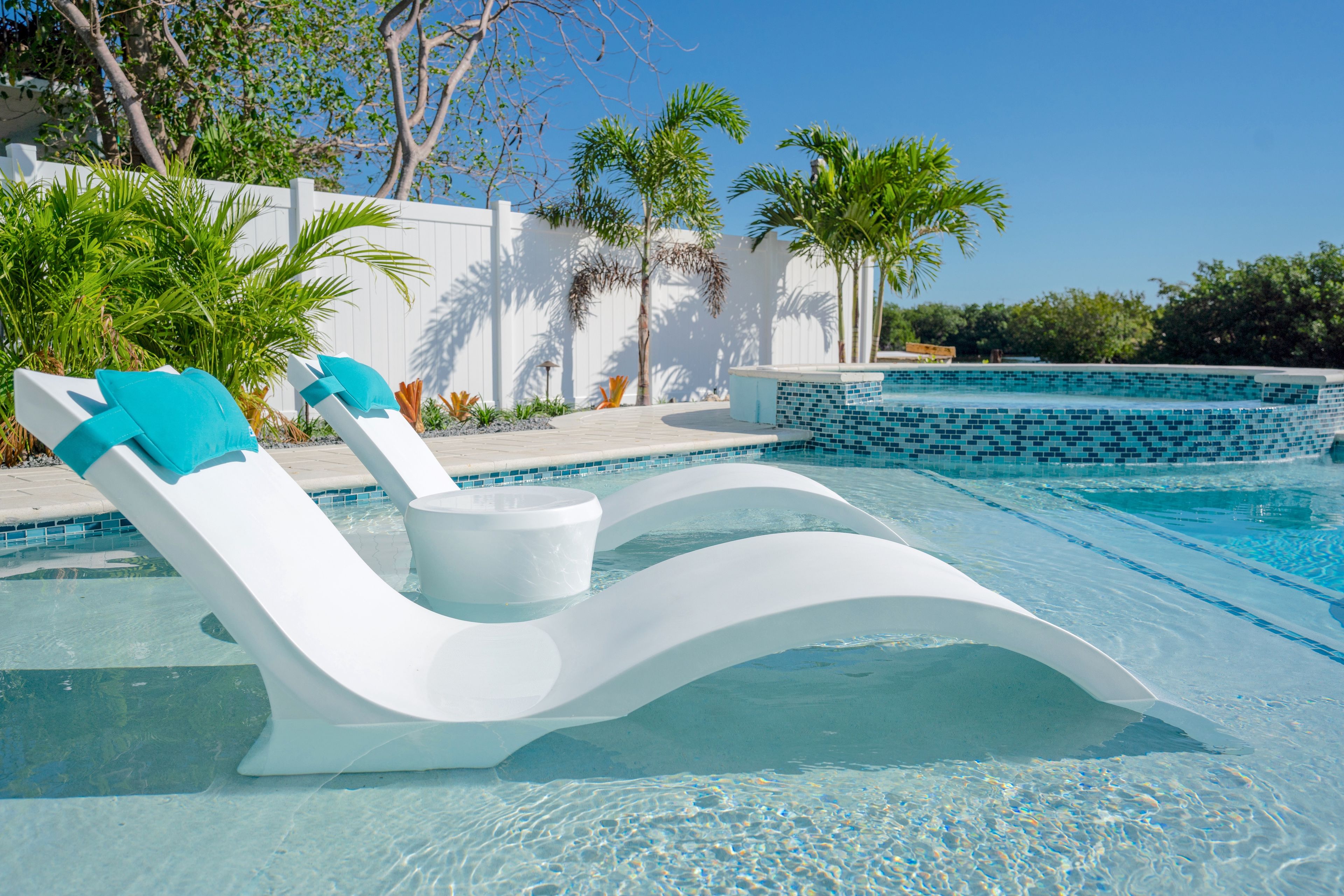 A swimming pool with a white lounge chair and a bucket.