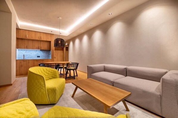 Una sala moderna con un sofá, una mesa de centro de madera y un sillón amarillo.