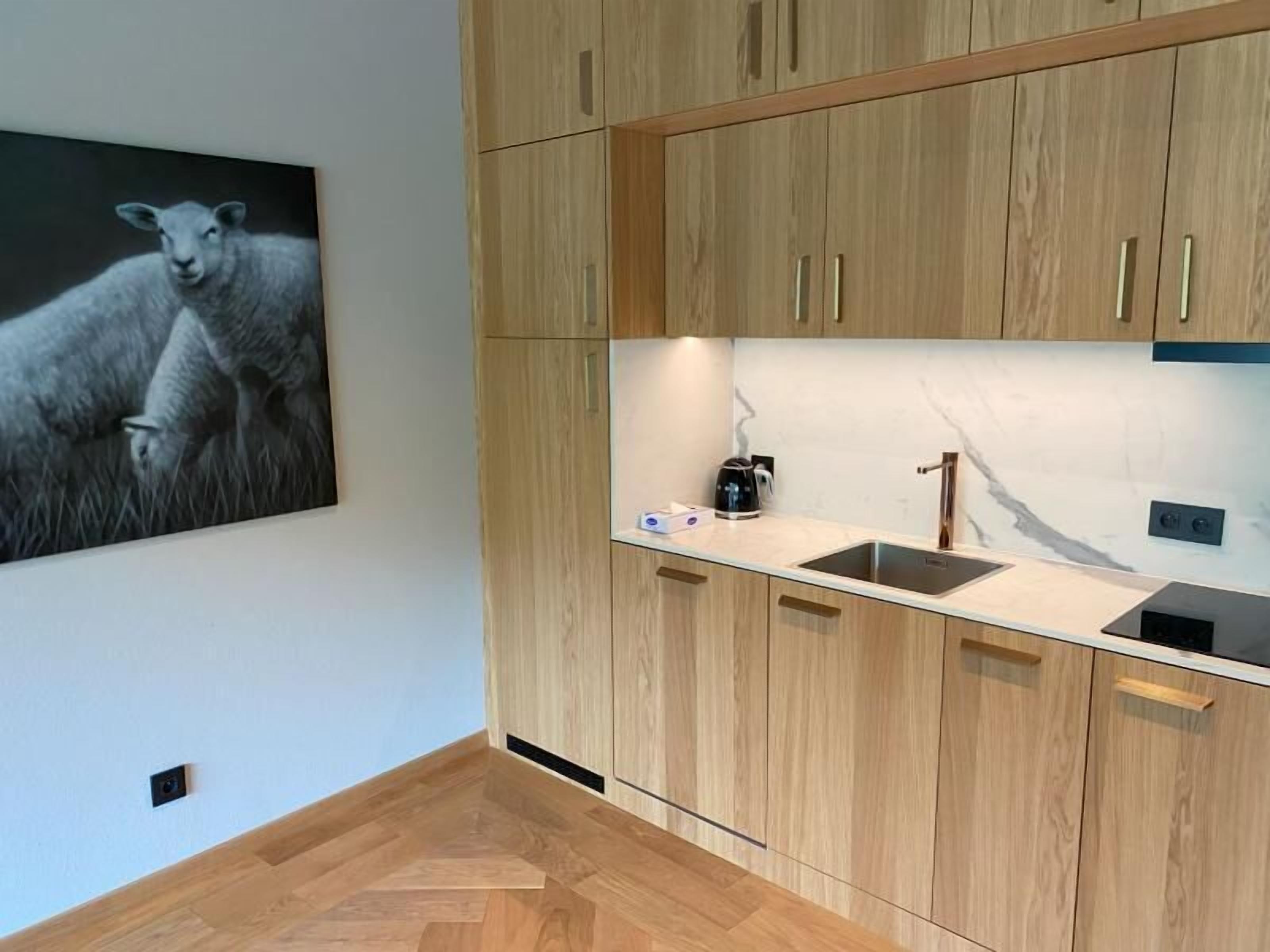 Una cocina moderna con armarios de madera, un protector contra salpicaduras de mármol y un hervidor negro sobre la encimera.