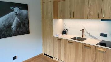 Una cocina moderna con armarios de madera, un protector contra salpicaduras de mármol y un hervidor negro sobre la encimera.