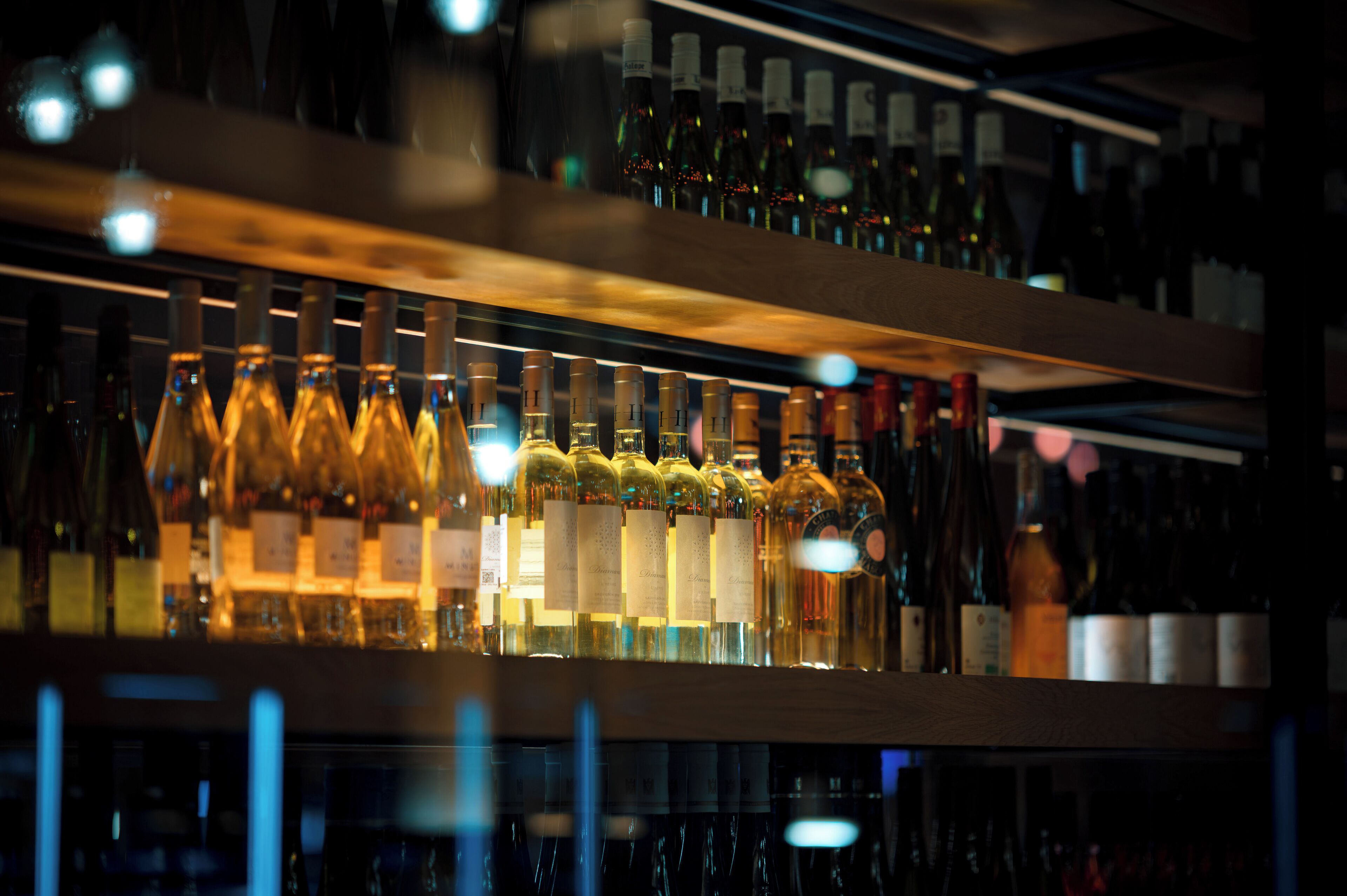 A bar with shelves of bottles, likely containing alcoholic beverages.