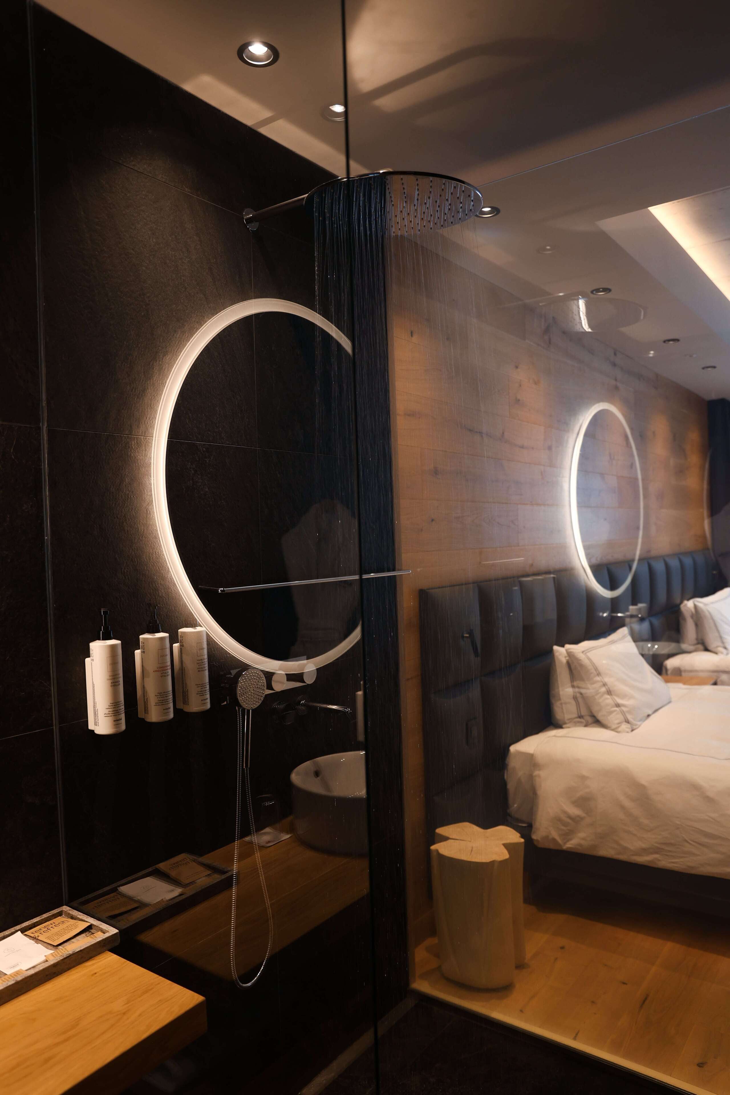 A modern bedroom with a large bed, a round mirror, and a wooden headboard.