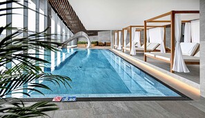 Una piscina de diseño moderno, con un muro curvo y sillones de descanso con toldos blancos.
