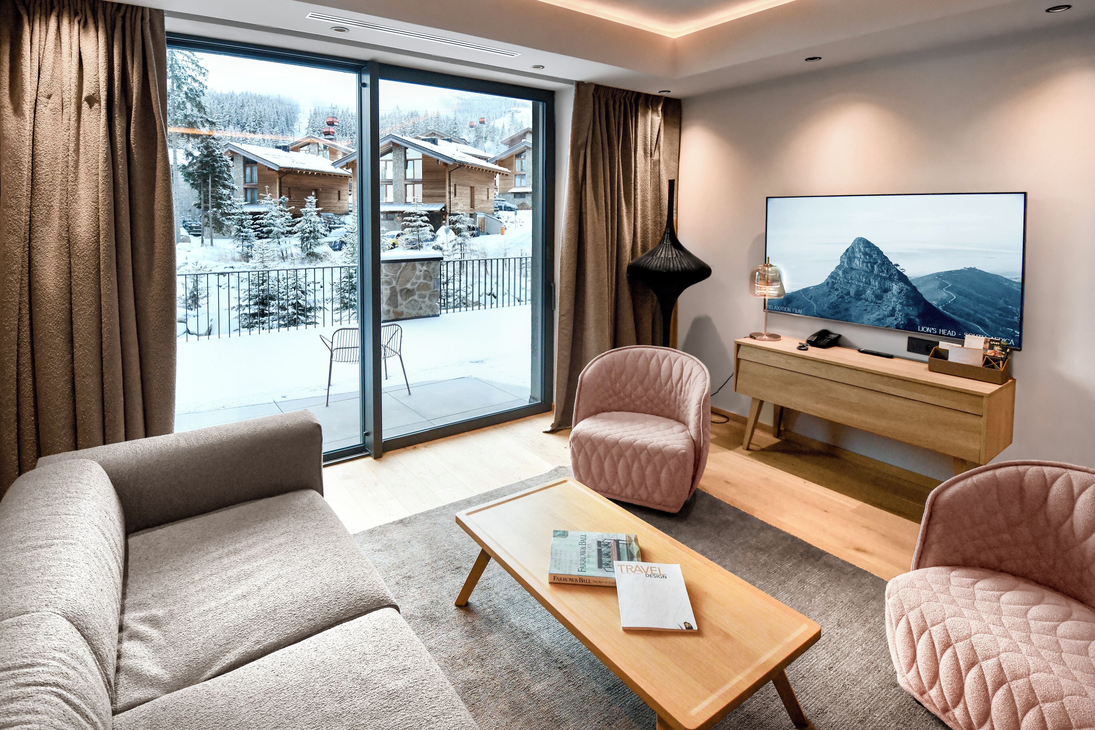 A modern living room with a sofa, armchairs, a coffee table, and a TV.