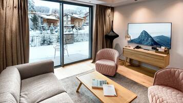 A modern living room with a sofa, armchairs, a coffee table, and a TV.