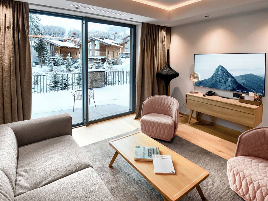 A modern living room with a sofa, armchairs, a coffee table, and a TV.