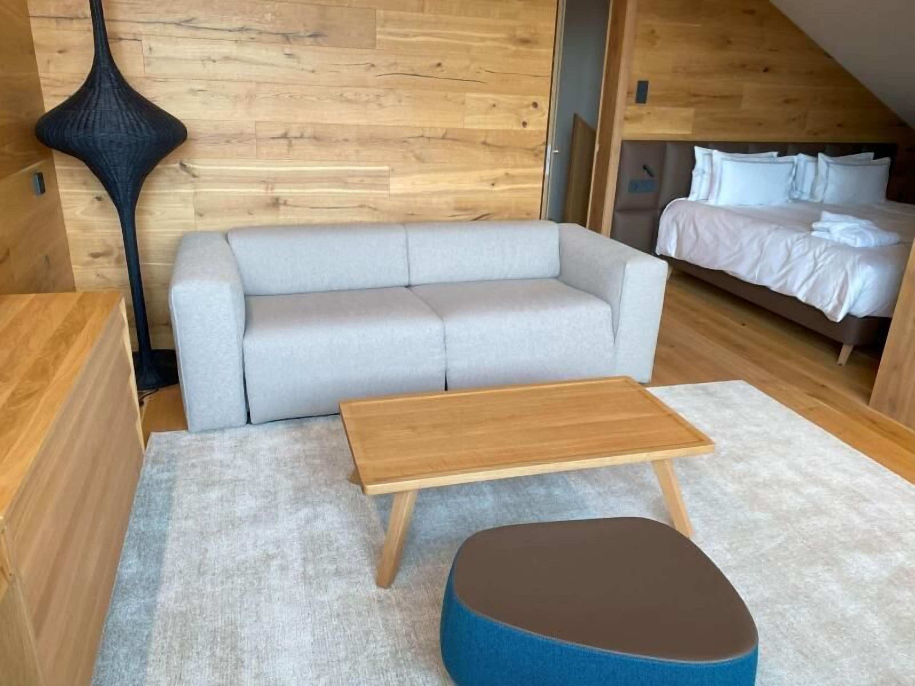 A compact room with a sofa, a small wooden table, and a blue ottoman.