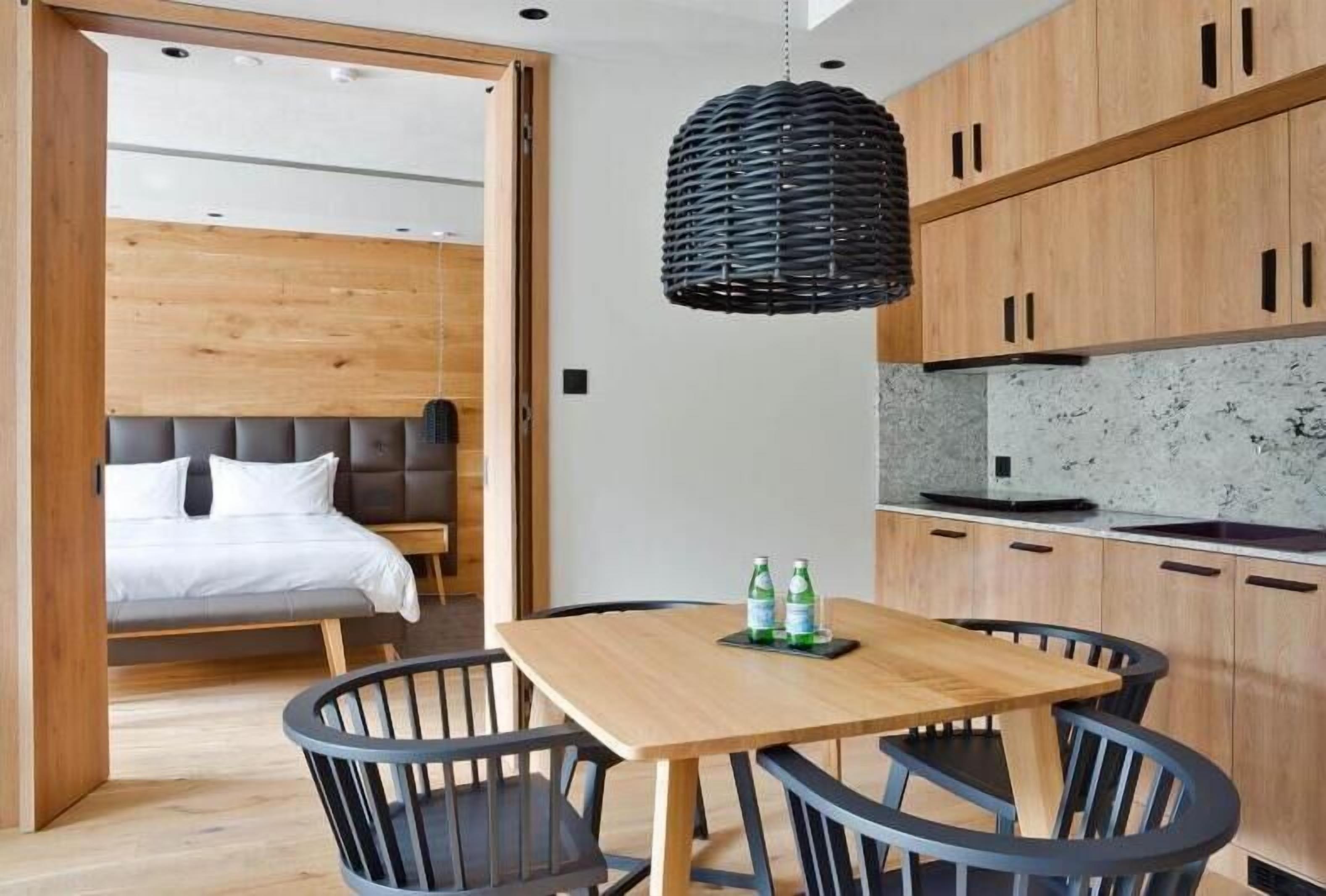 Eine moderne Küche mit Holzschränken, einer Marmorarbeitsplatte und einem Essbereich mit Holztisch und -stühlen.