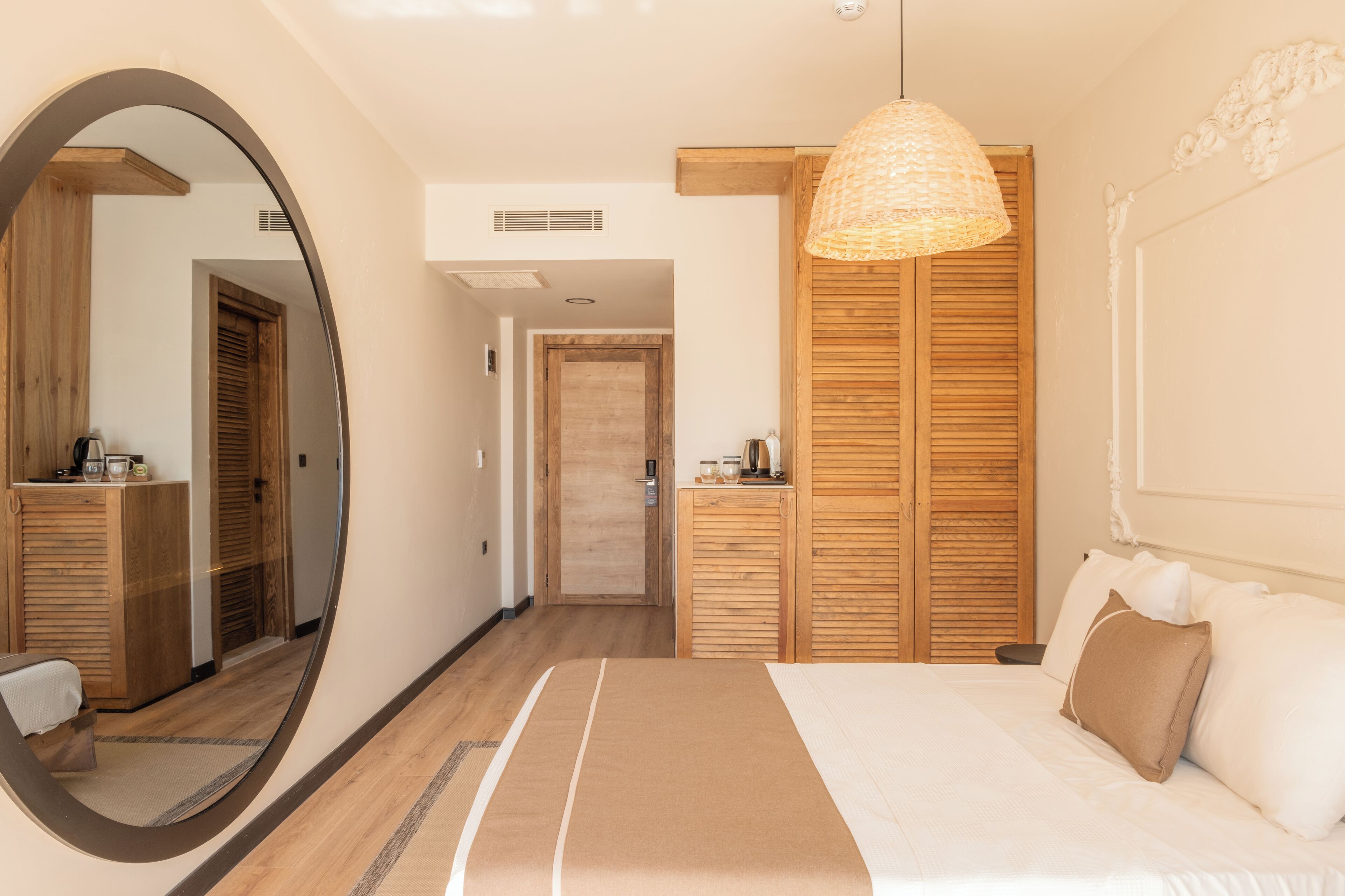 A bedroom with a large mirror, wooden wardrobe, and a hanging light fixture.