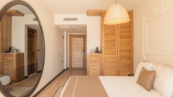 A bedroom with a large mirror, wooden wardrobe, and a hanging light fixture.