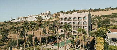 A resort with multiple buildings, a swimming pool, and palm trees.