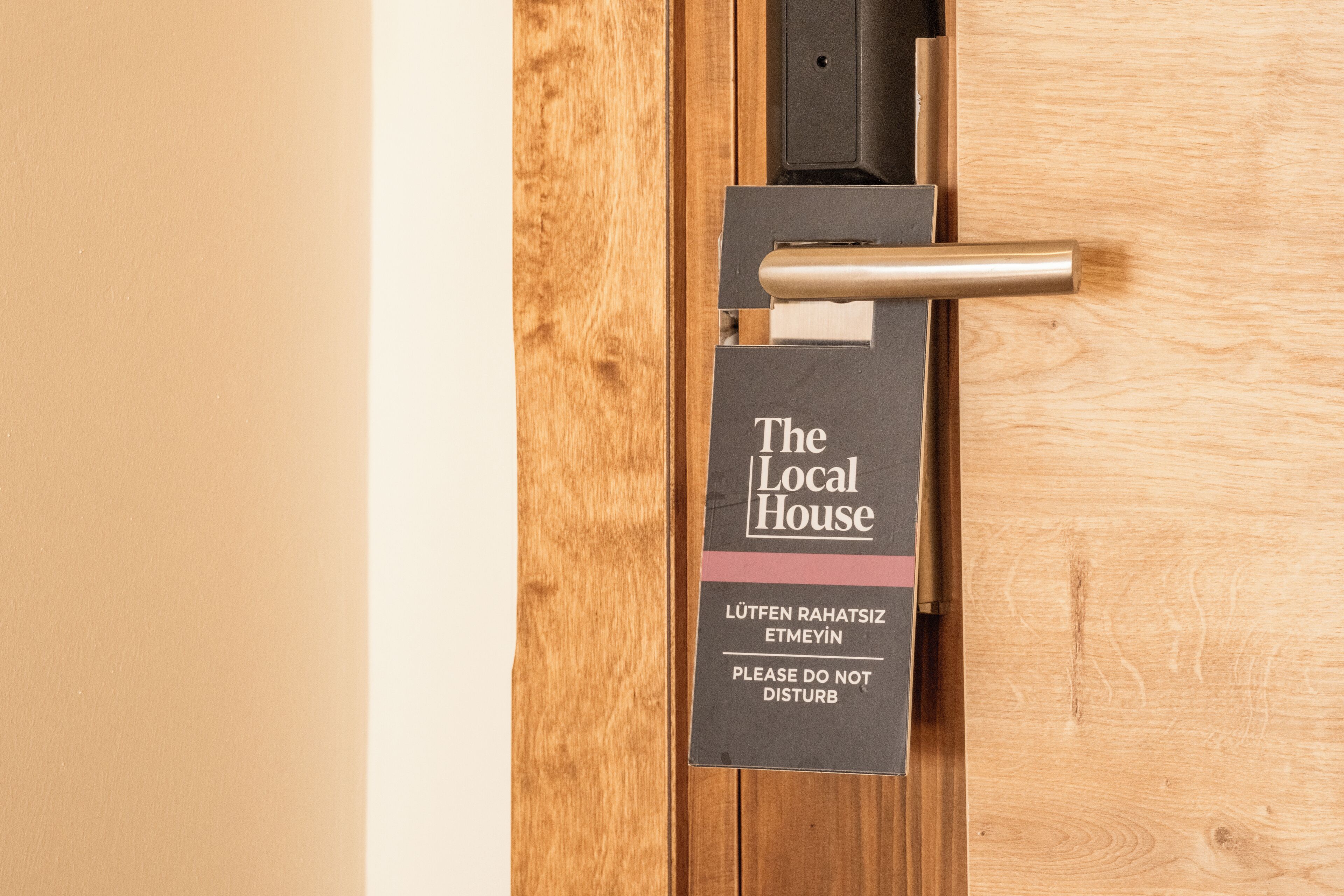 A door with a sign that reads "The Local House" and a note in another language.