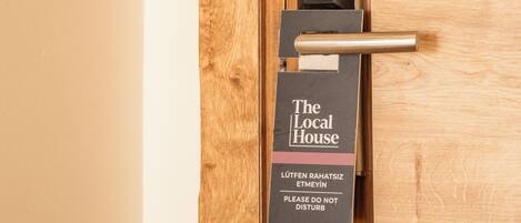 A door with a sign that reads "The Local House" and a note in another language.