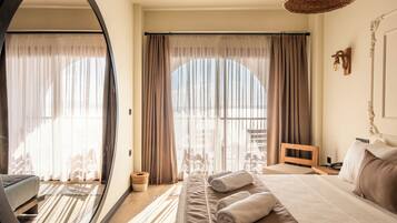 A hotel room with a large bed, a mirror, a wooden headboard, a wicker lamp, and a view of the outdoors through sheer curtains.