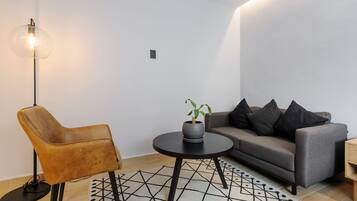 A modern living room with a sofa, a chair, a small table with a plant, and a floor lamp.